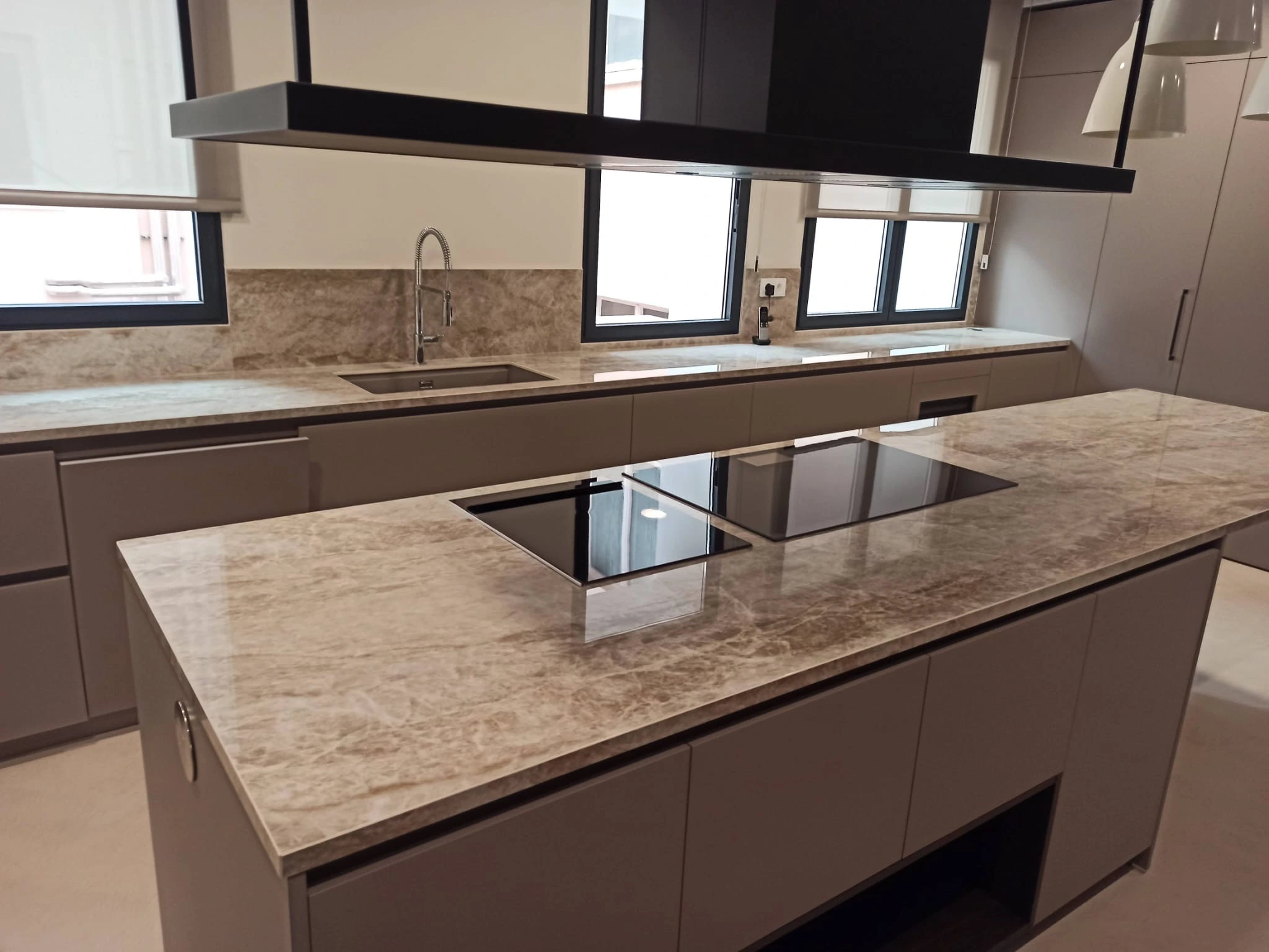 Cocina moderna con isla de mármol beige y campana negra - Ropema Rubio Madrid