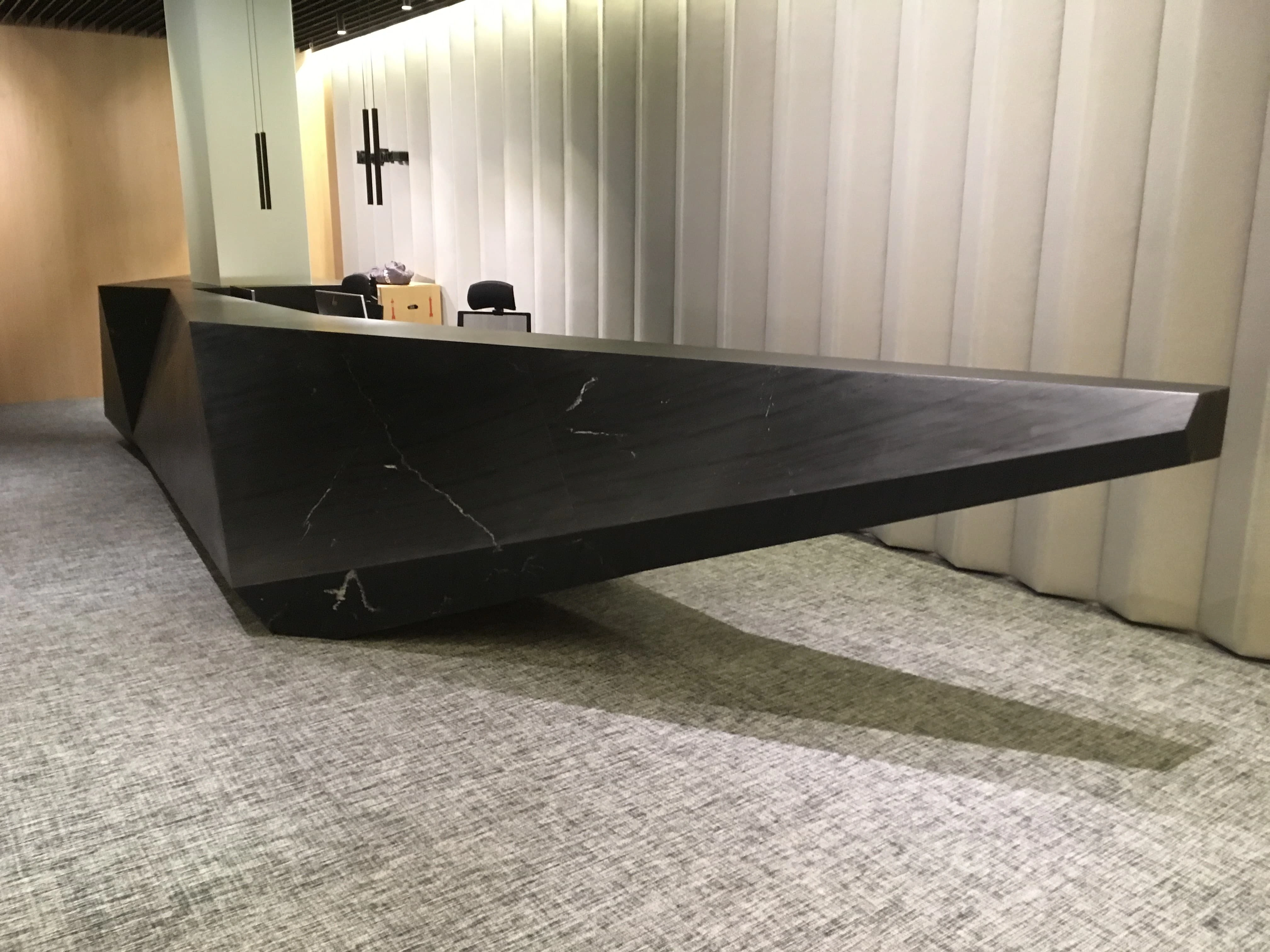 Mostrador de recepción flotante en mármol negro con vetas blancas - Ropema Rubio Madrid
